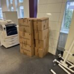 Empty cardboard boxes beside an office window with dismantled desks ready for end-of-lease clearance.