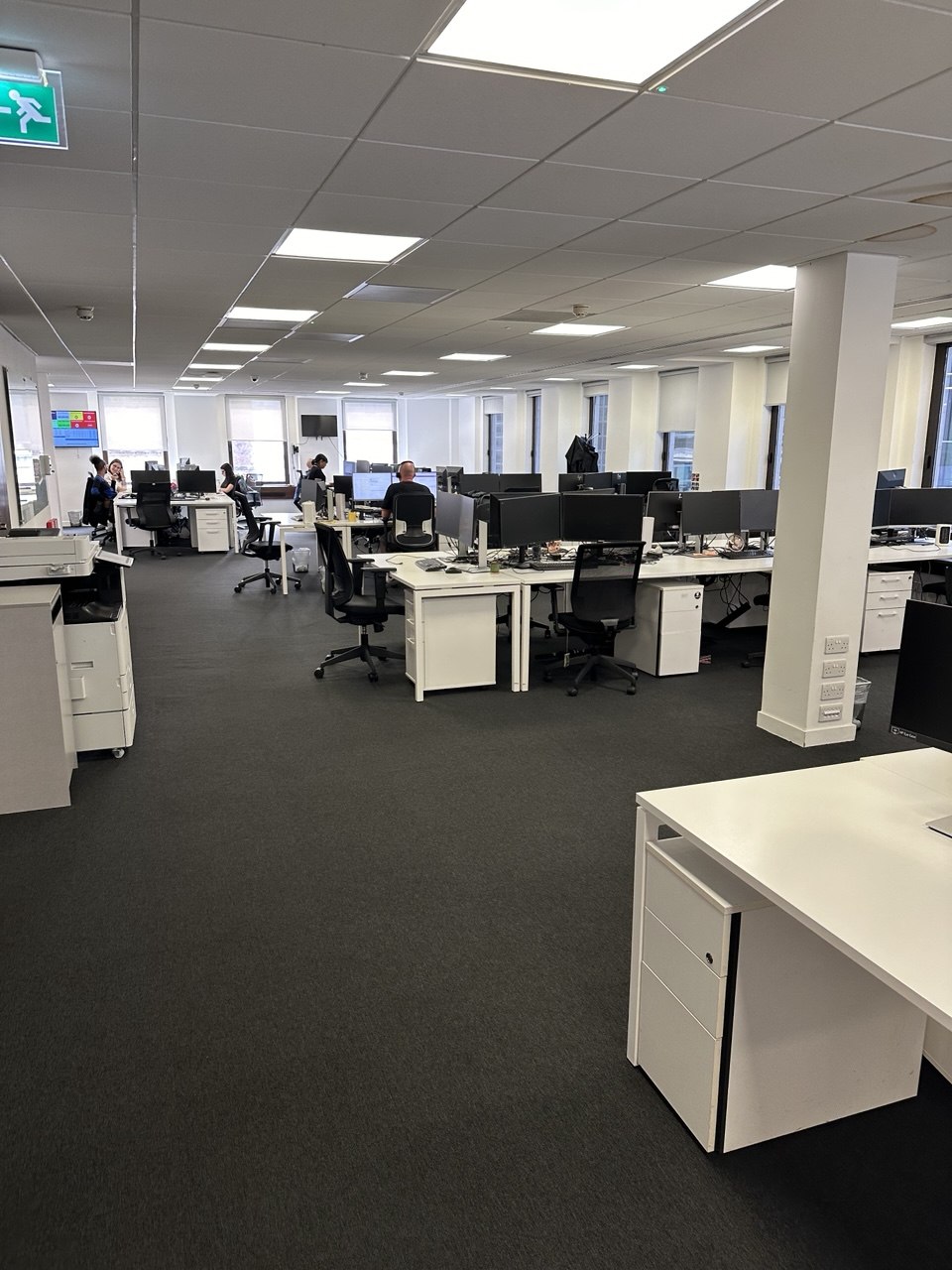 Open-plan commercial office with desks chairs and monitors before clearance